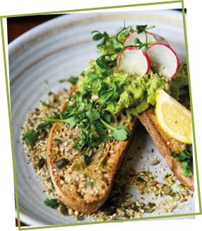 Brotscheiben mit grüner Guacamole und Radieschen